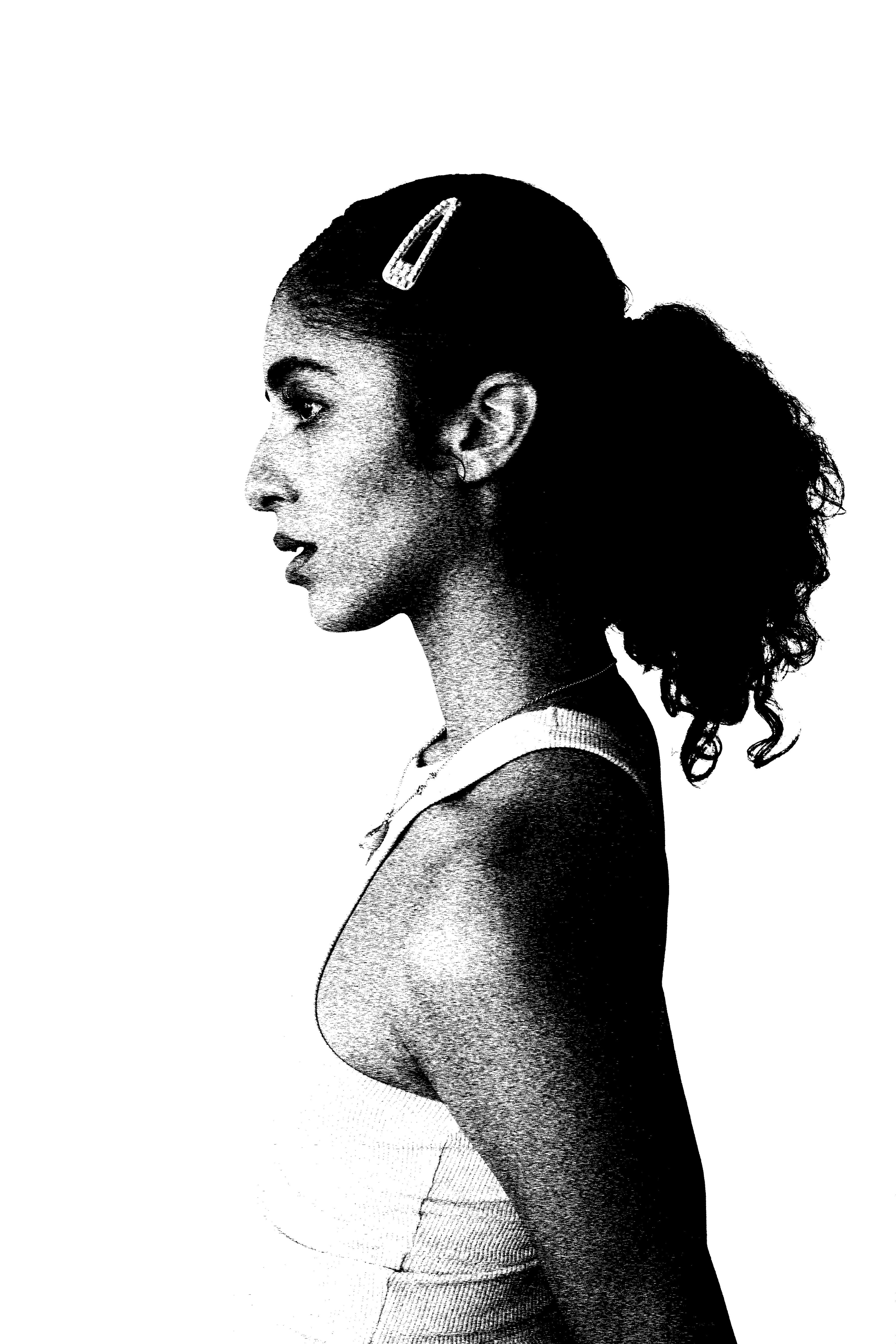 A model in profile against a white backdrop, hair tied back with a clip.